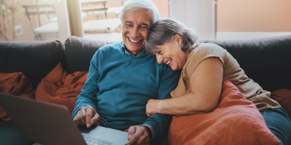 Retired couple watching funny video content on a laptop screen