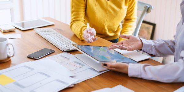 Two female designers drawing a website outline and website ux app development on mobile phone.